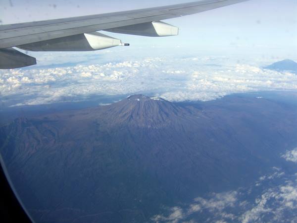 Airplane wing above Mount Teide volcano surrounded by clouds