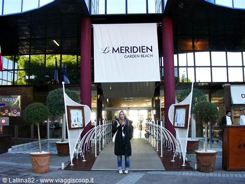 Smiling woman at the entrance of Le Méridien Garden Beach hotel with decorative plants