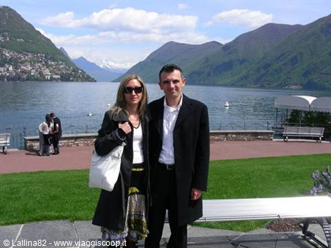 Couple posing on the Lugano lakefront, lake and mountains in the background