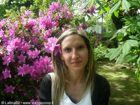 Smiling woman among blooming pink azaleas in a sunny garden