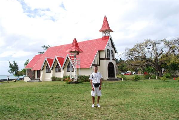 Man in white in front of the red-roofed church of Cap Malheureux