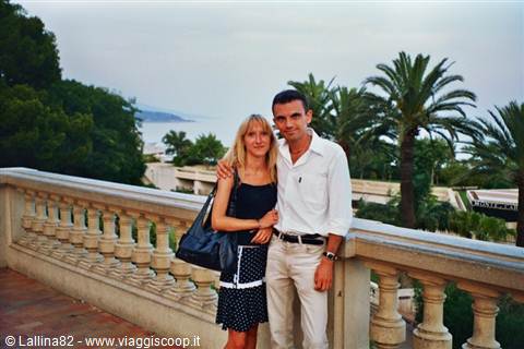 Couple on stone balustrade terrace with palm trees and sea behind