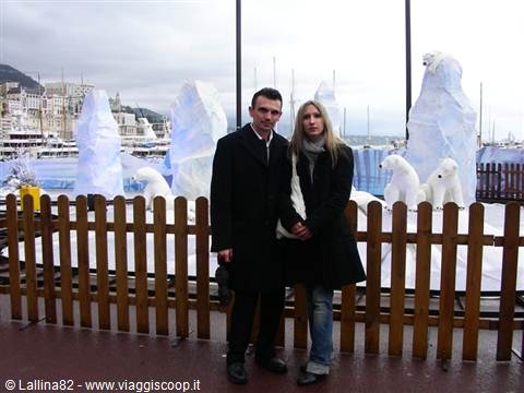Couple in coats posing by ice sculptures and polar bear decorations at Monaco harbor