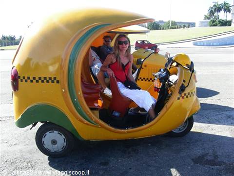 Smiling tourist inside yellow three-wheeled cocotaxi at Revolution Square Havana