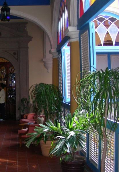 Colonial hallway with potted plants, stained glass windows and pink armchairs