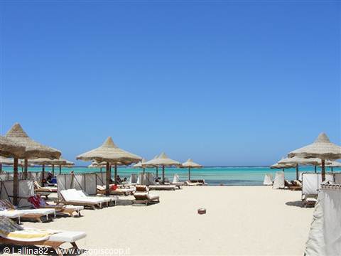 White sand beach with straw umbrellas and sunbeds facing the turquoise sea