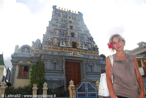 Woman in front of a colorful Hindu temple gopuram under cloudy sky