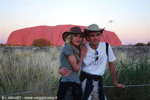 Couple in cowboy hats in front of red Uluru at dusk