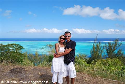 Couple embracing above Bora Bora's turquoise lagoon among green trees