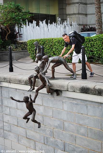 Tourist poses with bronze statues of boys jumping into the river, First Generation