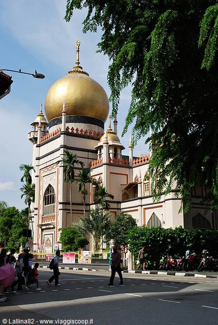 Sultan Mosque with its golden dome among trees, pedestrians crossing the street