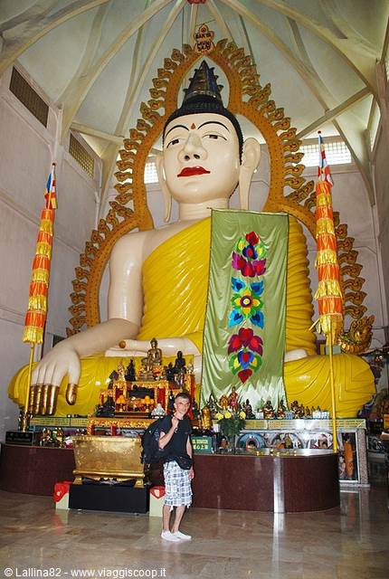 Tourist in front of the huge golden seated Buddha inside the temple