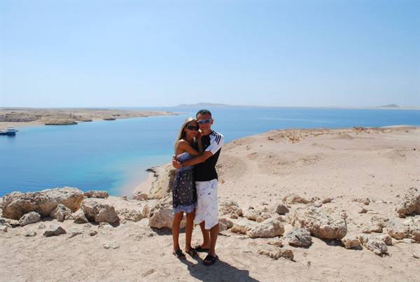 Couple embracing on sandy rocks overlooking the turquoise bay of Ras Mohammed