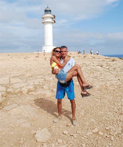 He lifts her in his arms before Barbaria lighthouse on arid rock