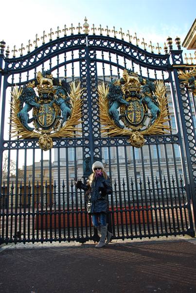 Tourist posing at the gilded gates of Buckingham Palace, London