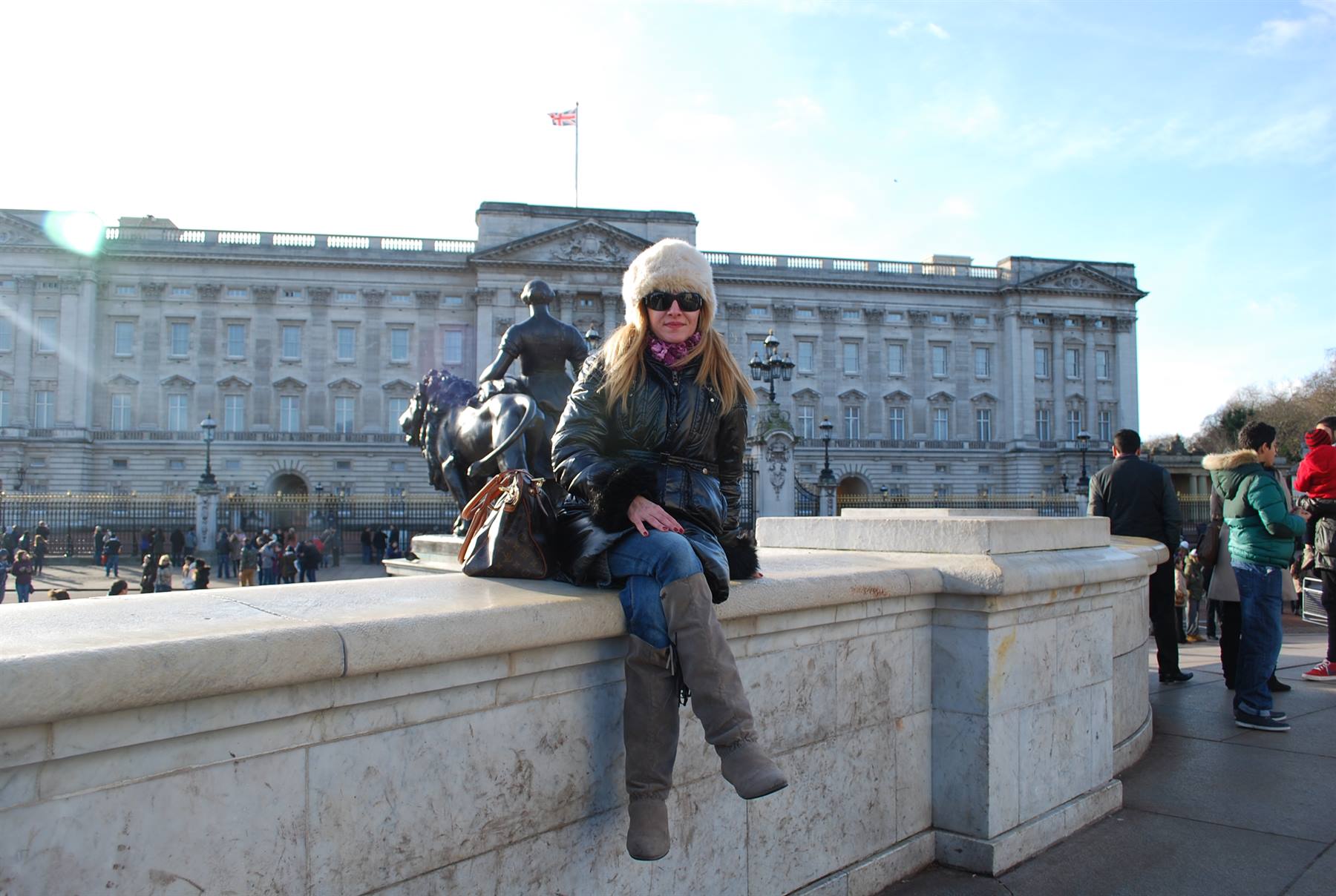 Turista seduta su un muretto di marmo davanti a Buckingham Palace, a Londra
