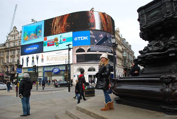 Woman in fur coat beneath the glowing billboards of Piccadilly Circus, London