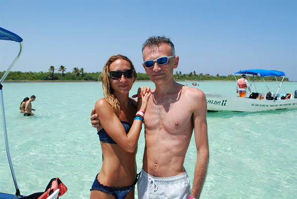 Couple embracing in turquoise water in front of tour boat