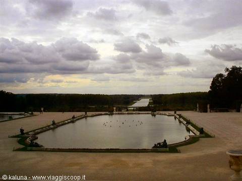 Stone pond with water birds in the gardens of Versailles, cloudy sky
