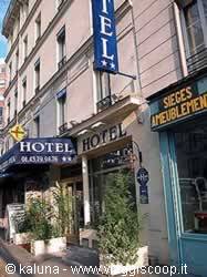 Blue hotel signs on Parisian facade, daylight, plants on the sidewalk