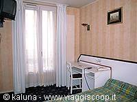 Hotel room with bed, desk, sink and curtained window