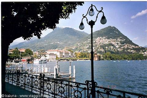 Lugano lakefront: wrought iron railing, street lamp and mountains across the water