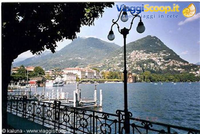 Lugano lakefront: wrought iron railing, street lamp and mountains across the water