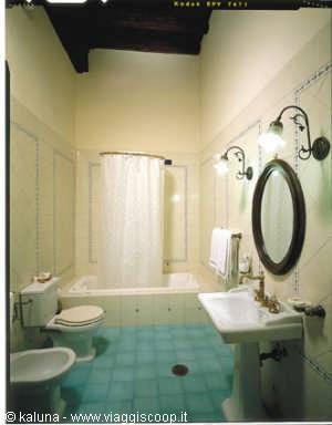 Classic bathroom with bathtub, bidet, small sink and oval mirror, blue floor