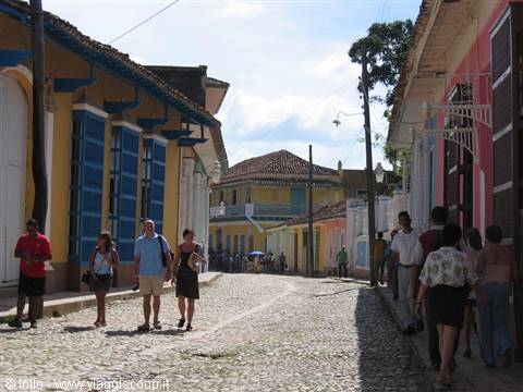 Tourists walk Trinidad's cobbled street lined with colorful colonial houses
