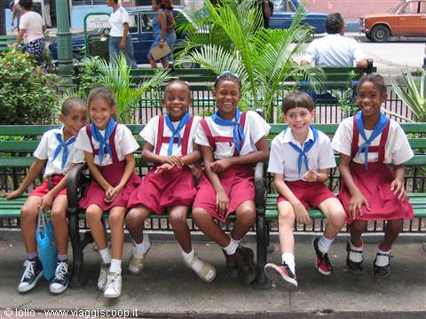 Schoolchildren in red uniforms sitting on a green bench