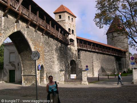 Medieval stone walls and towers in Tallinn, smiling woman in foreground