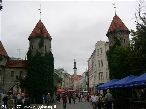 Viru Gate in Tallinn: two medieval stone towers with conical roofs, tourists in street