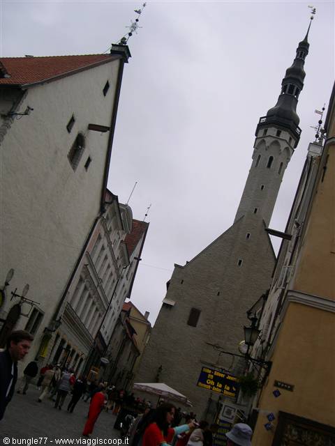 Tourists in Tallinn's medieval town hall square beneath the tall stone tower
