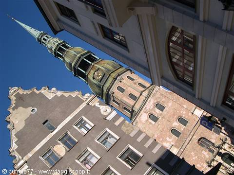 Green spire of St. Peter's church rising between baroque buildings in Riga