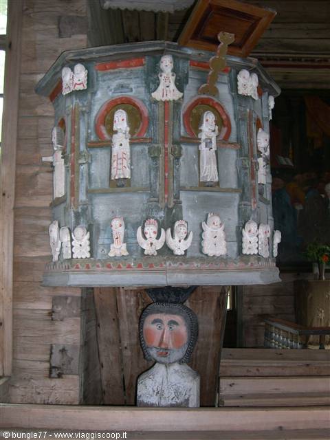 Painted wooden pulpit with carved saints, supported by a sculpted head, wooden church