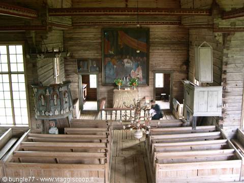 Wooden church interior with pews, pulpit and painting above the altar