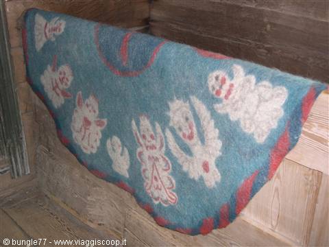 Blue felt rug with white figures, draped over a wooden bench