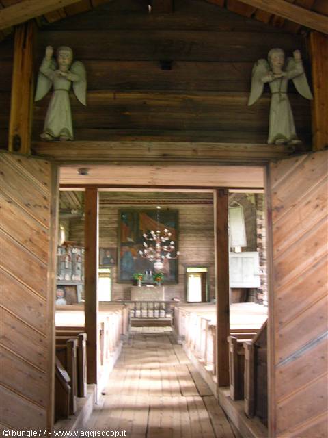 Petäjävesi wooden church: carved angels above the door, sunlight on pews