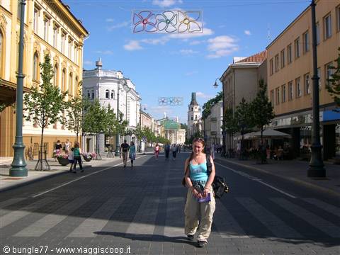 Girl with backpack walking along Gediminas Avenue, Vilnius, colorful lights overhead