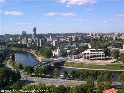 Neris river with arched bridge among Vilnius modern buildings, sunny daylight