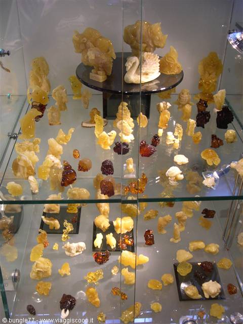 Glass case displaying carved amber figurines in yellow and brown tones