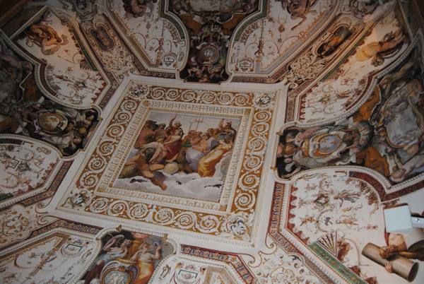 Frescoed ceiling with mythological scenes and golden stuccoes under warm artificial light