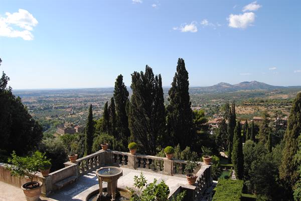 Stone terrace with fountain and potted plants among cypresses above Tivoli valley