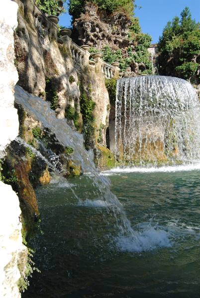 Fountain with water cascades over mossy rocks in historic garden