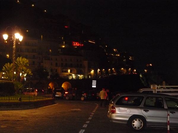 Parked cars at night in front of the illuminated Amalfi hillside village