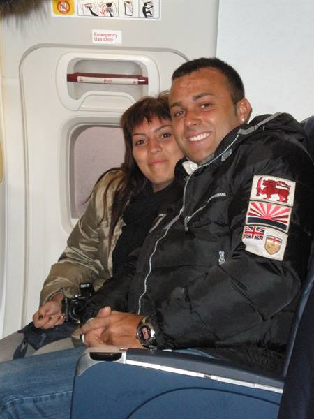 Smiling couple beside the emergency exit row on an airplane, camera in hand
