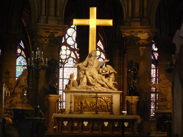 Pietà statue beneath golden cross, Gothic stained glass in Notre-Dame de Paris