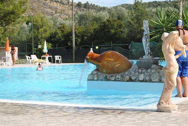 Pool with terracotta amphora pouring water, statues and white loungers