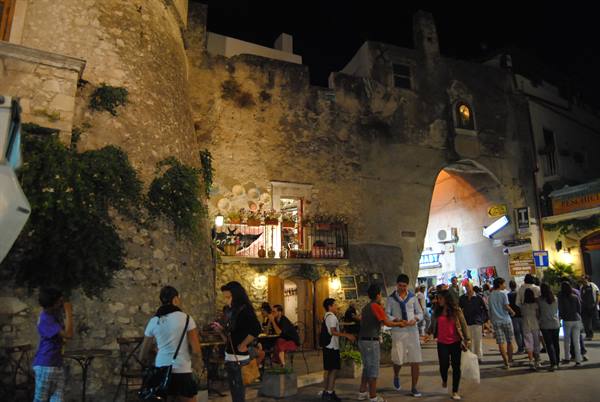 Tourists stroll at night beneath Sperlonga's ancient stone gate