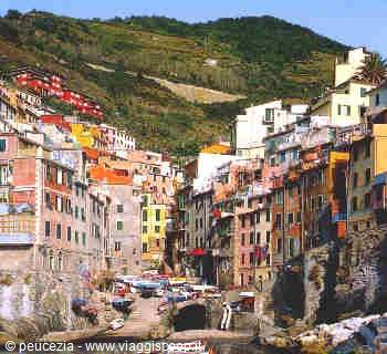 Colorful houses of Riomaggiore on the Cinque Terre hills, with boats in the harbor